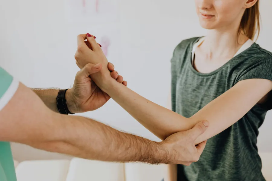 A healthcare professional supports a patient's arm during a physical rehabilitation session